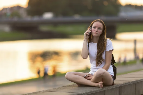 ウォーター フロントに座っているかわいい若い女の子 — ストック写真