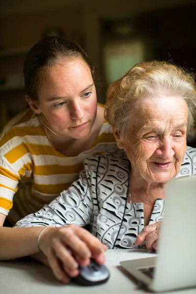 Enkelin mit Großmutter in der Nähe des Computers. — Stockfoto
