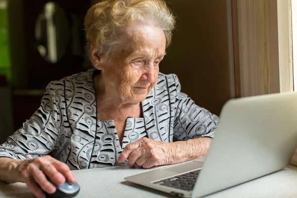Bir dizüstü bilgisayarda çalışan yaşlı kadın. — Stok fotoğraf