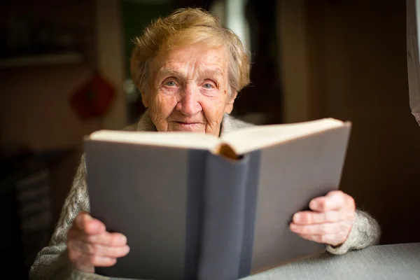 Пожилая женщина читает большую книгу — стоковое фото