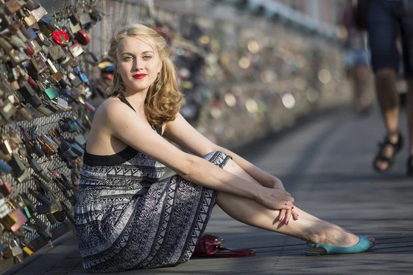 Woman sitting on bridge of love in Krakow. — Stock Photo, Image