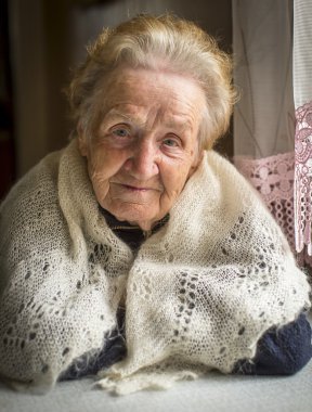 Yaşlı kadın masada oturuyor..