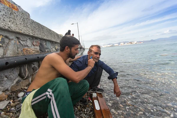 Unidentified refugees shaves the other — 스톡 사진