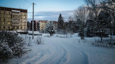 Kuzey Rusya 'da kış yerleşim bölgesi. Karla kaplı zemin, apartmanlar, park edilmiş arabalar, ağaçlar ve soğuk mavi gün ışığı altında sessiz bir patika..