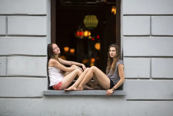 Meninas sentadas no peitoril da janela — Fotografia de Stock