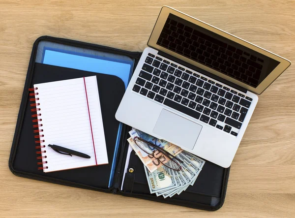 Business case with laptop, notebook and dollars/euros bills
