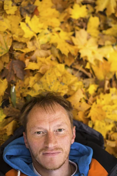 Sonbahar yaprakları üzerinde yatan adam. — Stok fotoğraf