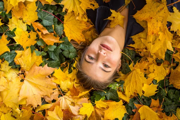 Mädchen liegt auf abgefallenem Laub — Stockfoto