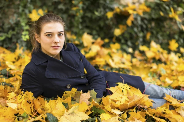 Ragazza sdraiata in foglie cadute — Foto Stock