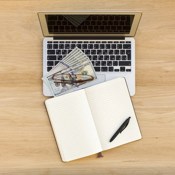 Ноутбук, ноутбук с ручкой и долларовыми купюрами — стоковое фото
