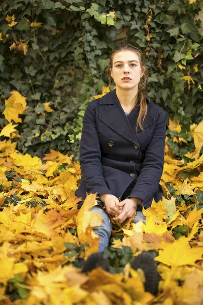 Fille assise sur les feuilles tombées — Photo