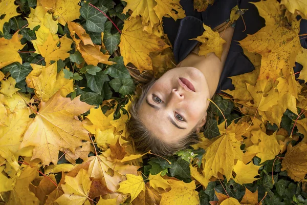 Chica acostada en las hojas de otoño . — Foto de Stock