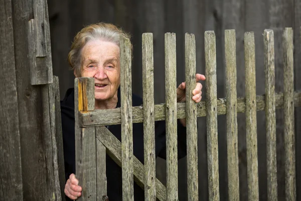 Oude vrouw in de buurt van een hek — Stockfoto