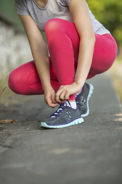 スポーティな女の子のスニーカーの靴ひもを結ぶ — ストック写真