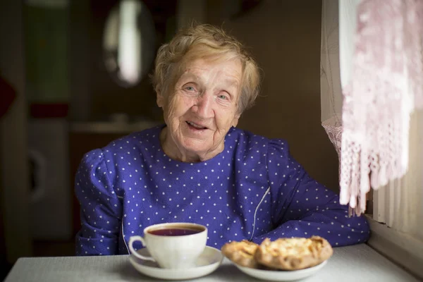 Old woman drinking tea — Stock Photo, Image