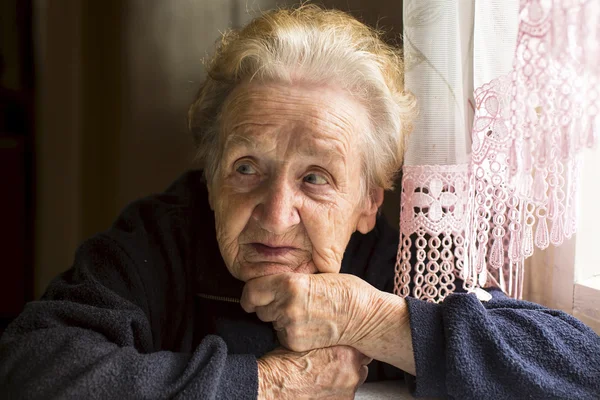 Vieja sentada cerca de la ventana — Foto de Stock