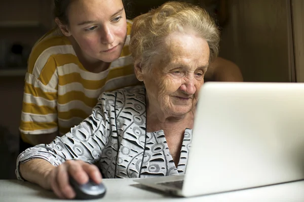 Mogen kvinna wiith barnbarn arbete på datorn. — Stockfoto