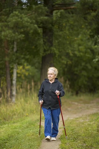 Mature woman walking in the green array — Stock Photo, Image