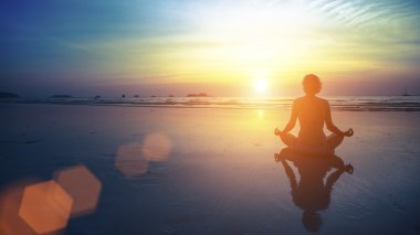 Yoga yapan kadın kumsalda poz veriyor.