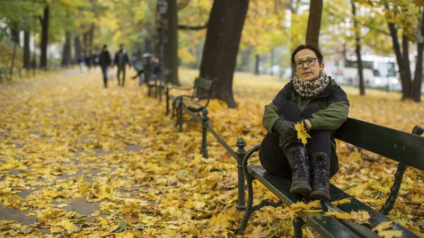 Kvinnan sitter på en bänk — Stockfoto