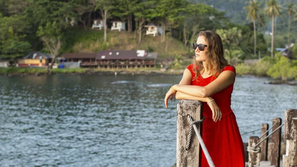 Flicka i röd klänning på en träbro — Stockfoto