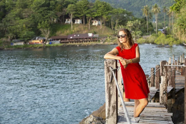 Menina em vestido vermelho na ponte de madeira — Fotografia de Stock