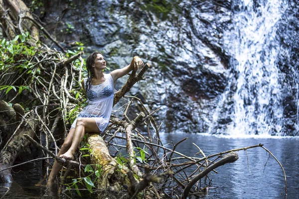 Frau sitzt in der Nähe des Wasserfalls — Stockfoto