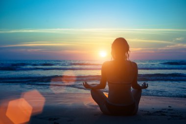 Kadın plajda yoga yapıyor.