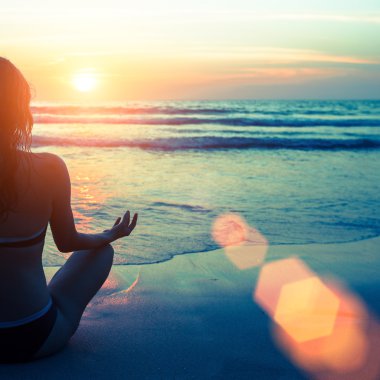 Kadın plajda yoga yapıyor.