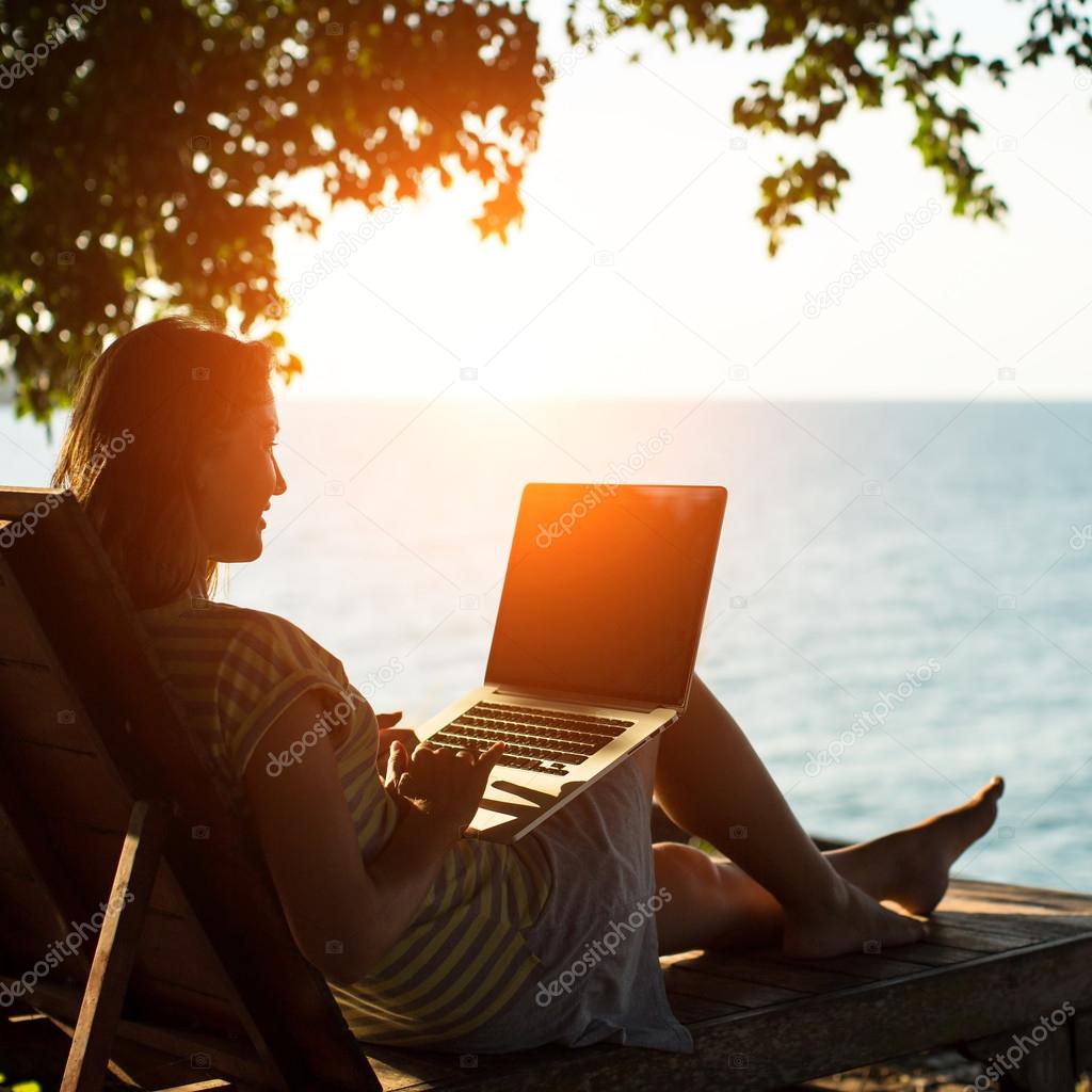 woman on a sun lounger with a laptop