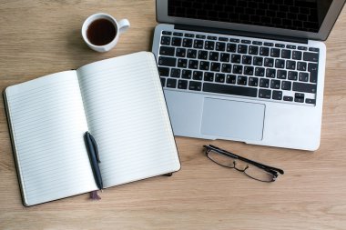 Kalem ve ahşap masa üstünde laptop ile not etmek