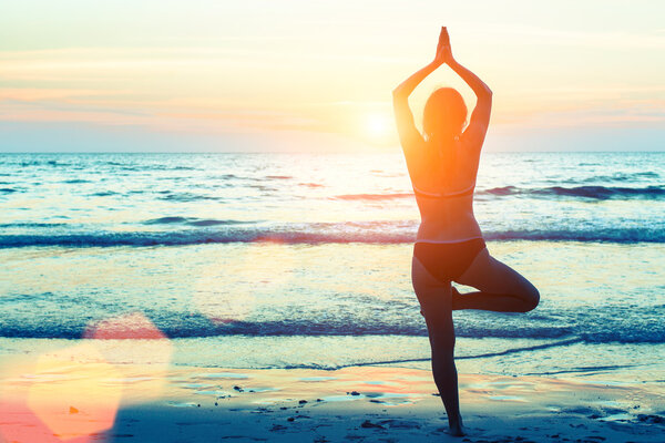 woman in yoga pose on the beach