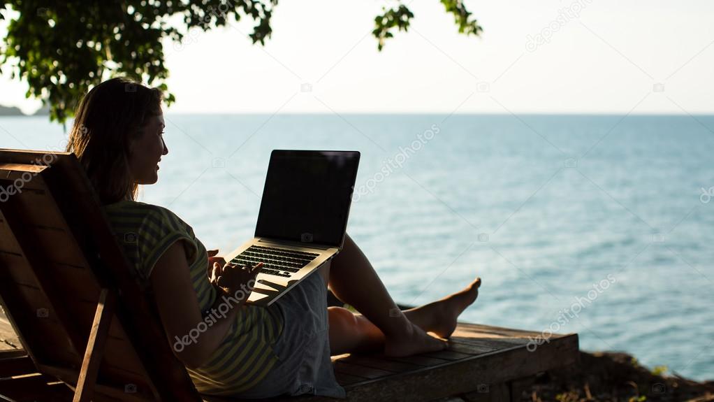 woman on a sun lounger with a laptop