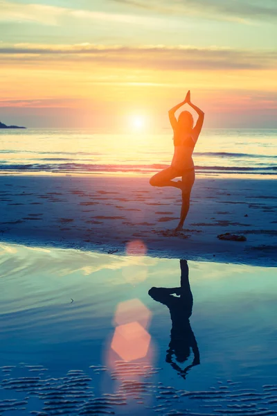 Vrouw in yoga poseren op het strand — Stockfoto