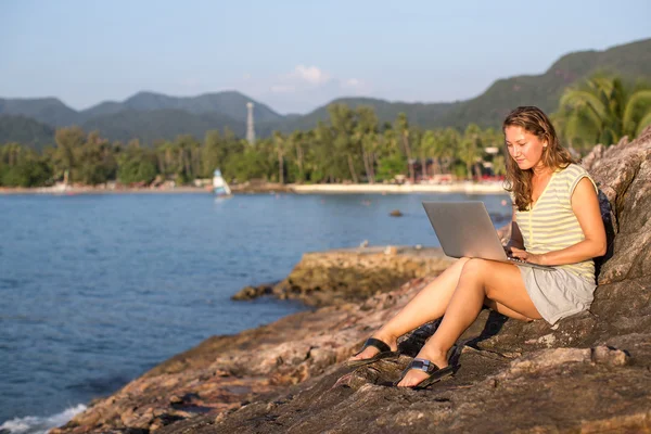 Женщина, сидящая на берегу моря с ноутбуком — стоковое фото
