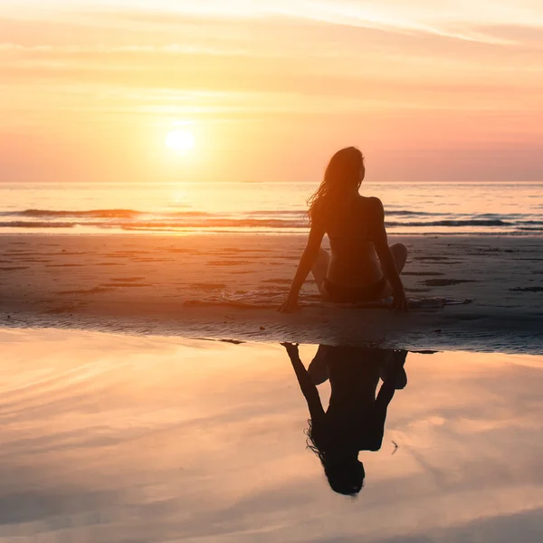 Kobieta siedzi na plaży podczas — Zdjęcie stockowe