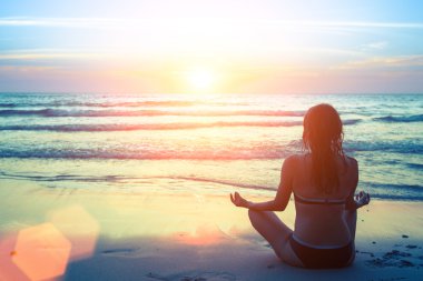 Kadın plajda yoga yapıyor.