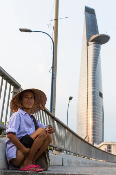 Poor vietnamese and Bitexco Financial Tower — Stock Photo, Image