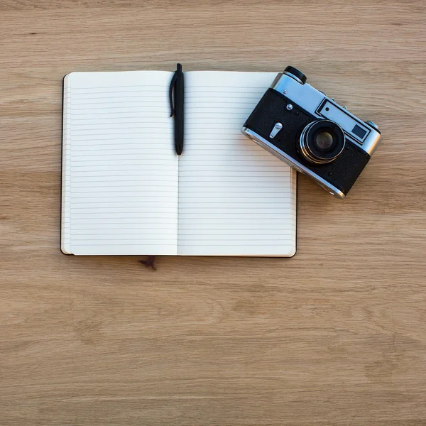Notepad with pen and film camera on table — Stock Photo, Image