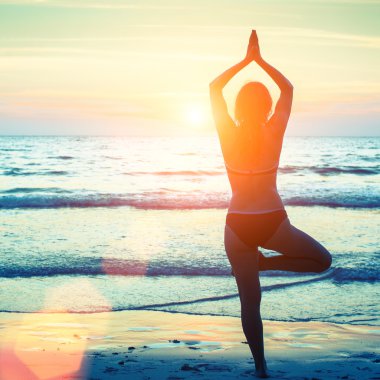 Yoga yapan kadın kumsalda poz veriyor.