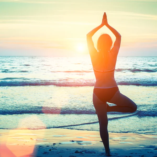 Kvinna i yoga poserar på stranden — Stockfoto