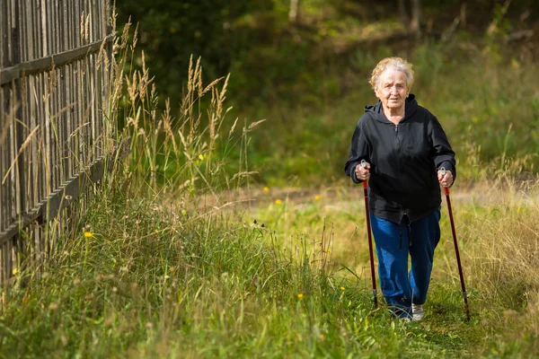 Starší žena procházky v parku. — Stock fotografie