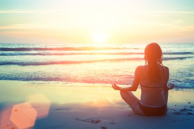 Kadın plajda yoga yapıyor.