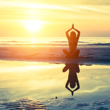 Kadın plajda yoga yapıyor.