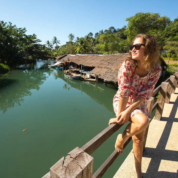 Mulher sentada na ponte sobre o rio — Fotografia de Stock