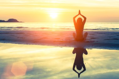 Woman doing meditation on the beach.