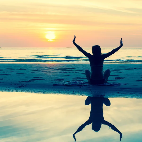 Vrouw zittend op het strand bij zonsondergang — Stockfoto