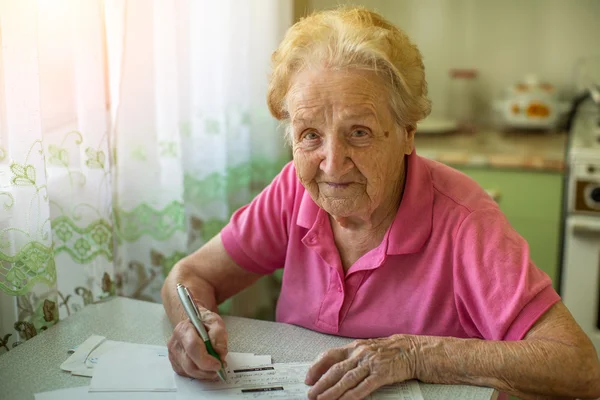 Äldre kvinna fyller räkningar — Stockfoto