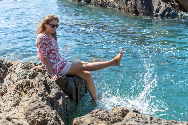 Woman sitting on coastal rocks — Zdjęcie stockowe