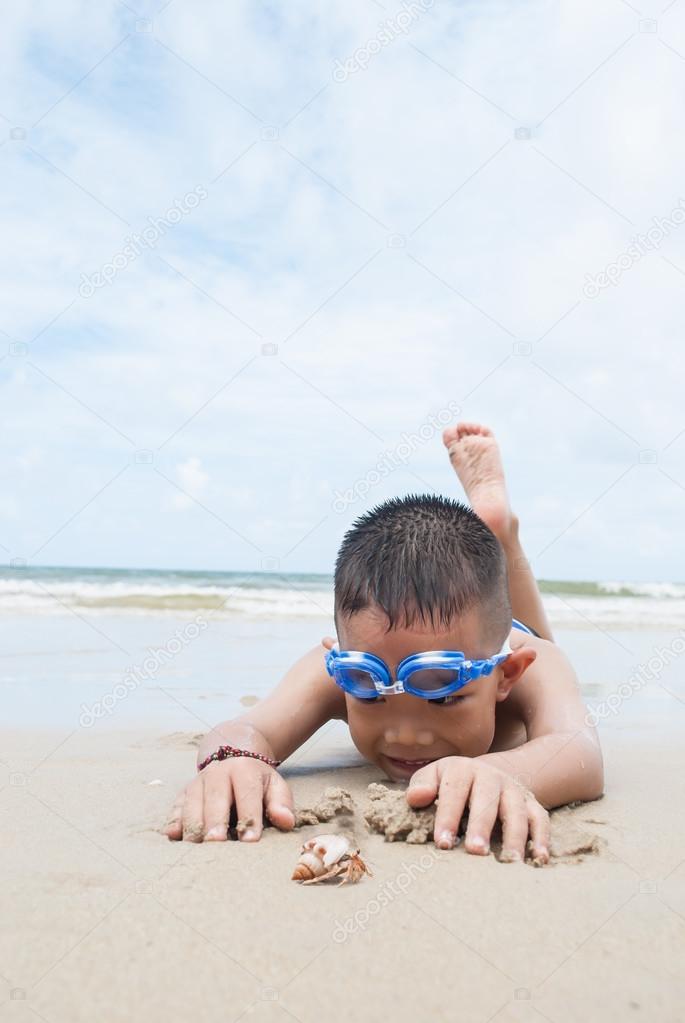 playful boy and Hermit crab on the beach with sea  on background